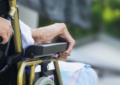 Aide soignant poussant un fauteuil roulant